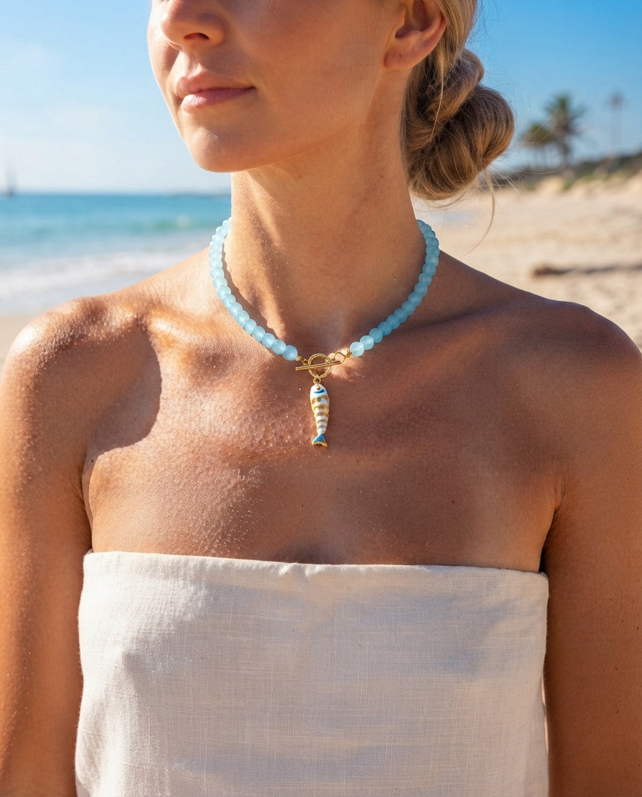 Dark green beaded koi fish necklace worn on a beach
