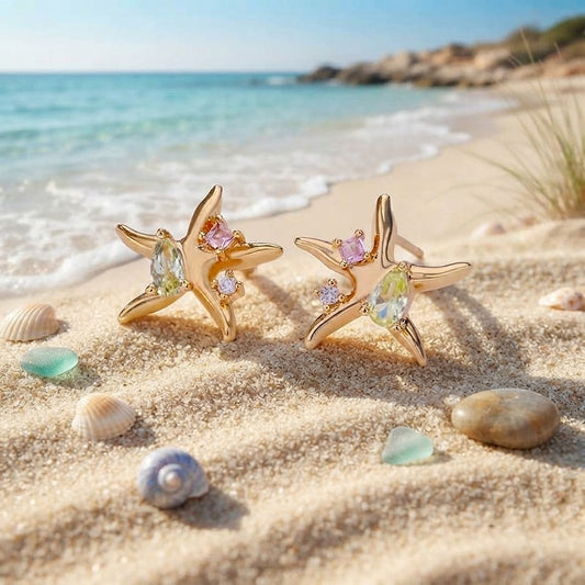 Gold starfish stud earrings with pastel zircon on sand