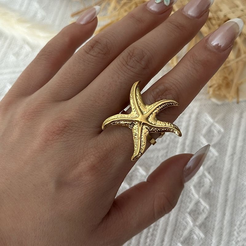 Gold textured starfish ring worn on the hand