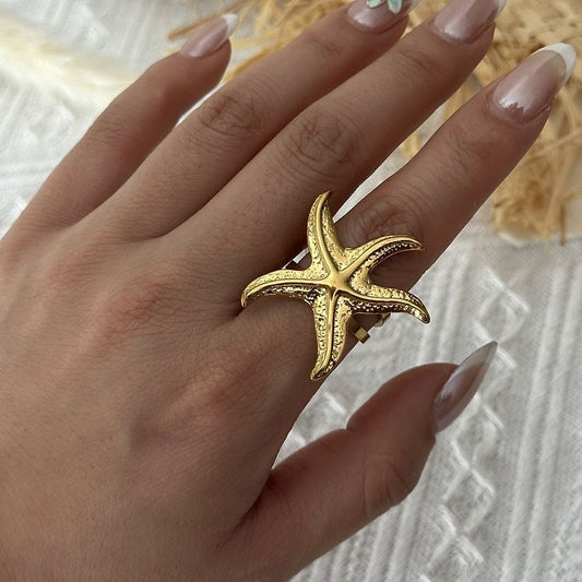 Gold textured starfish ring worn on the hand