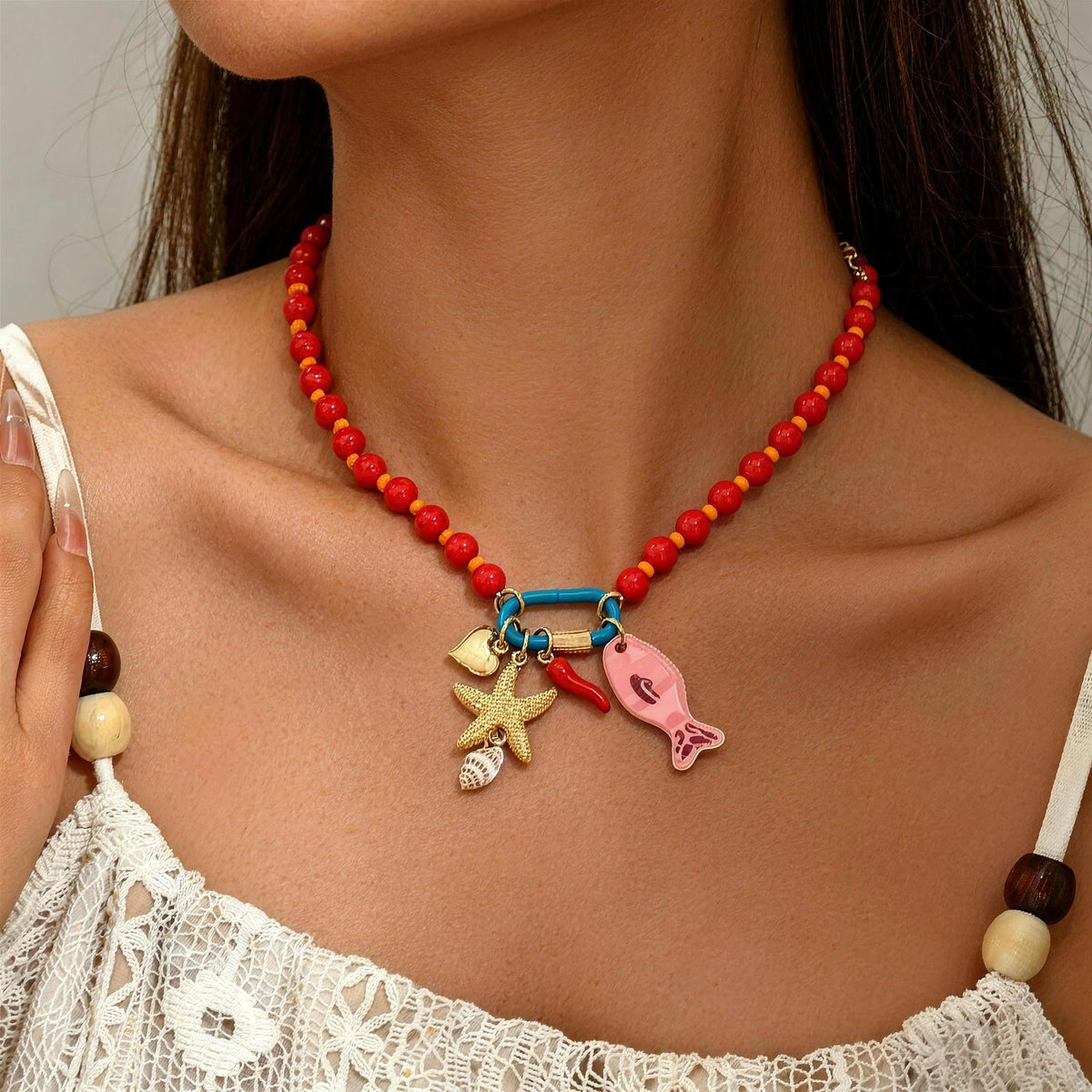 Red beaded starfish and fish charm-holder necklace worn with white lace