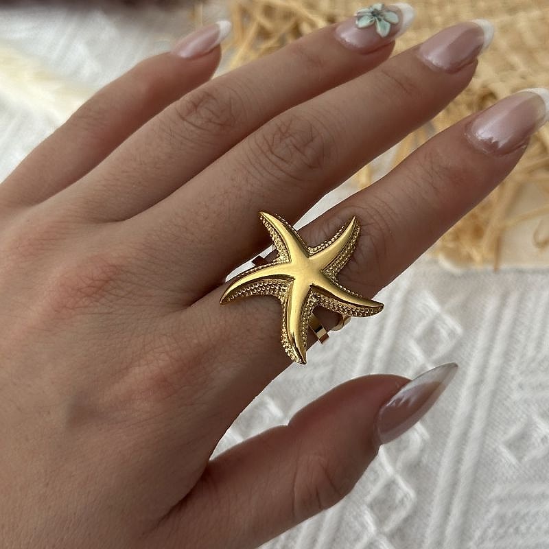 Gold starfish ring with textured band worn on the hand