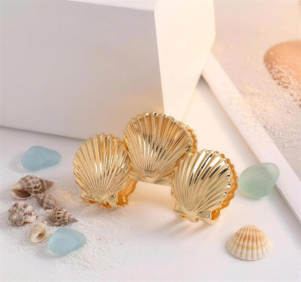 Gold clam shell hair claw beside sea glass and shells