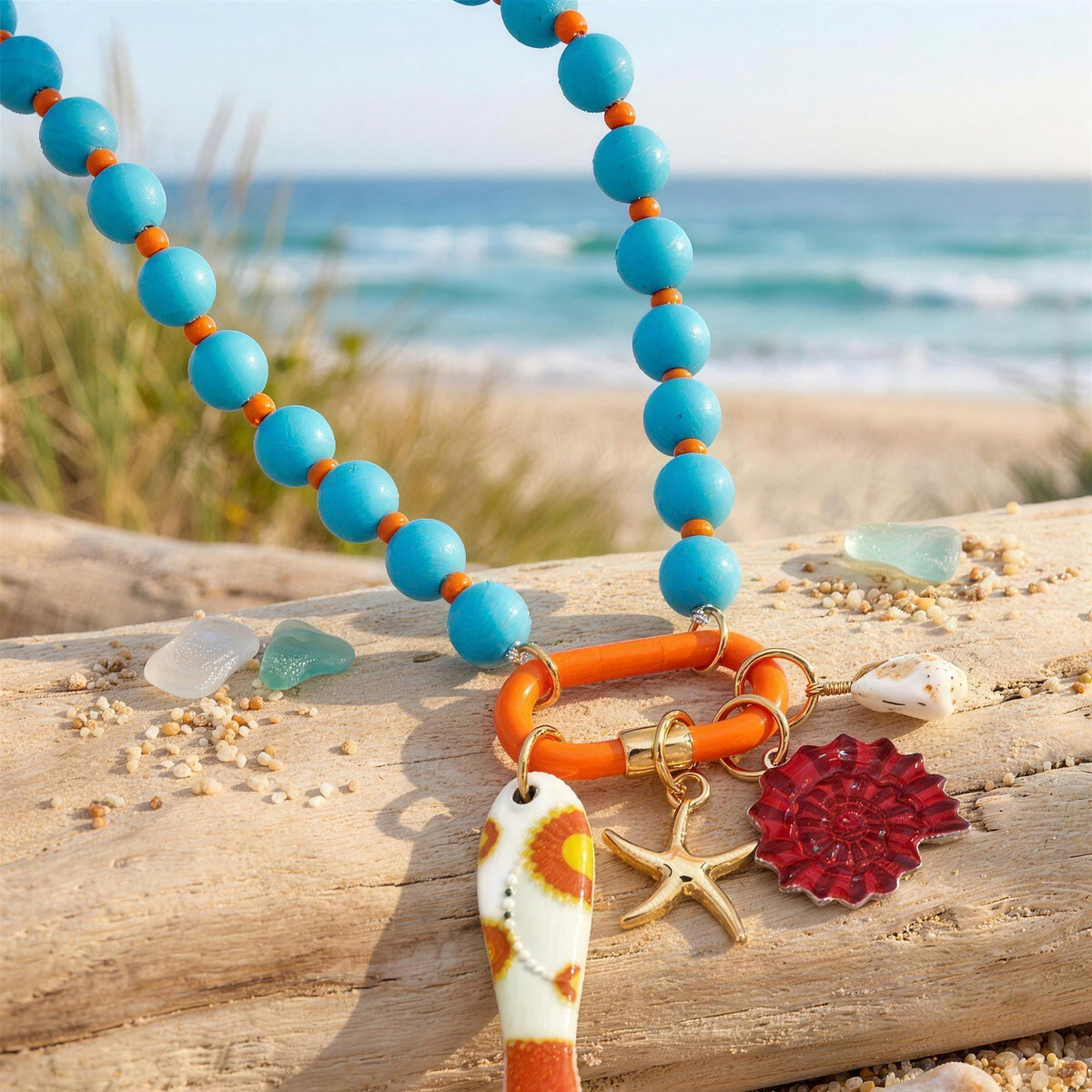Turquoise beaded charm-holder necklace with fish and spiral shell charms on driftwood