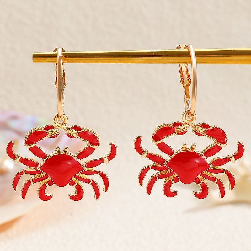 Red enamel crab hoop earrings hanging on a gold bar