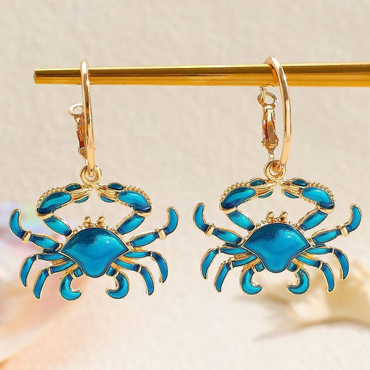 Blue enamel crab hoop earrings hanging on a gold bar