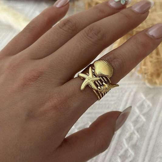 Gold starfish, scallop and shell ring worn on the hand